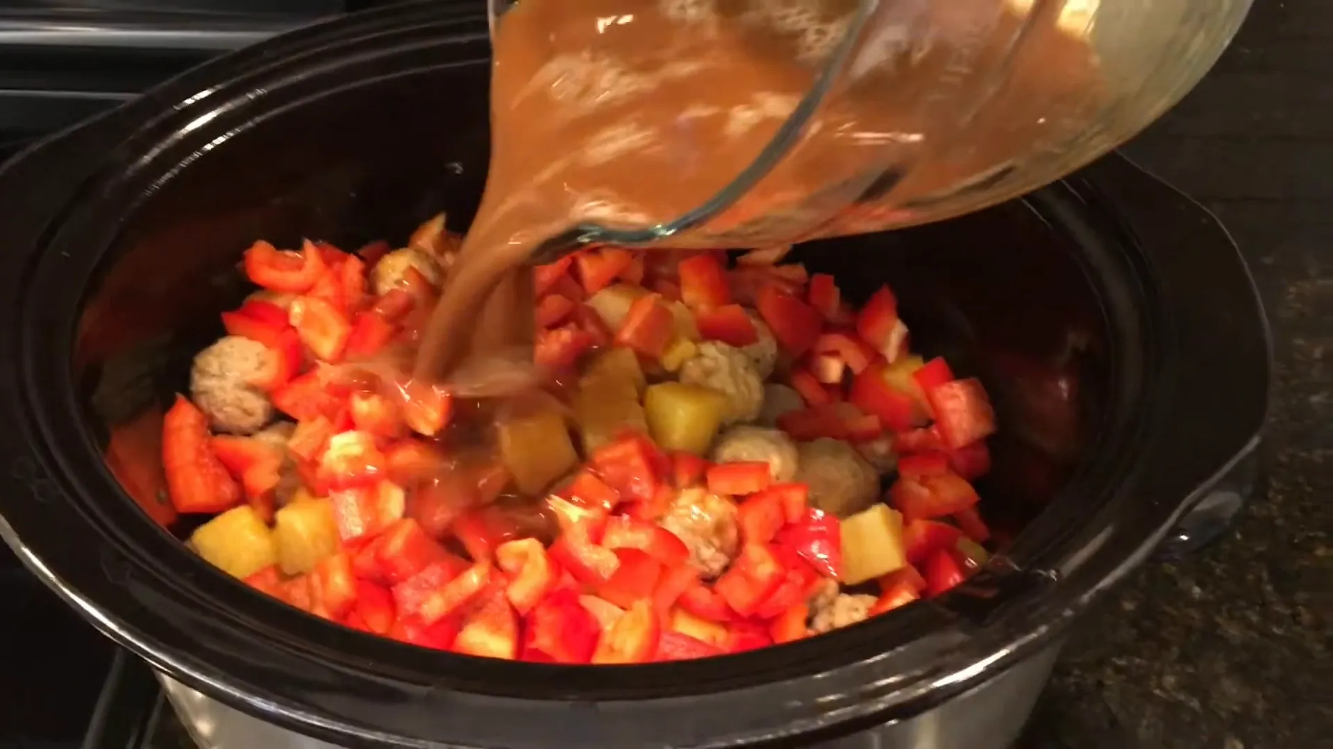 Pouring the sauce over the meatballs.