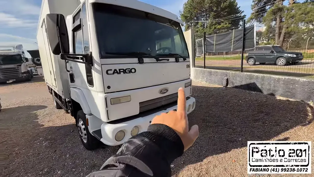 Caminhão Ford Cargo branco com baú refrigerado estacionado no pátio