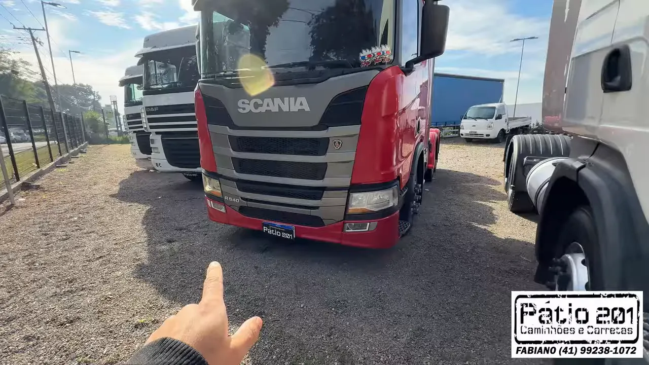 Cavalo mecânico Scania vermelho estacionado entre caminhões brancos