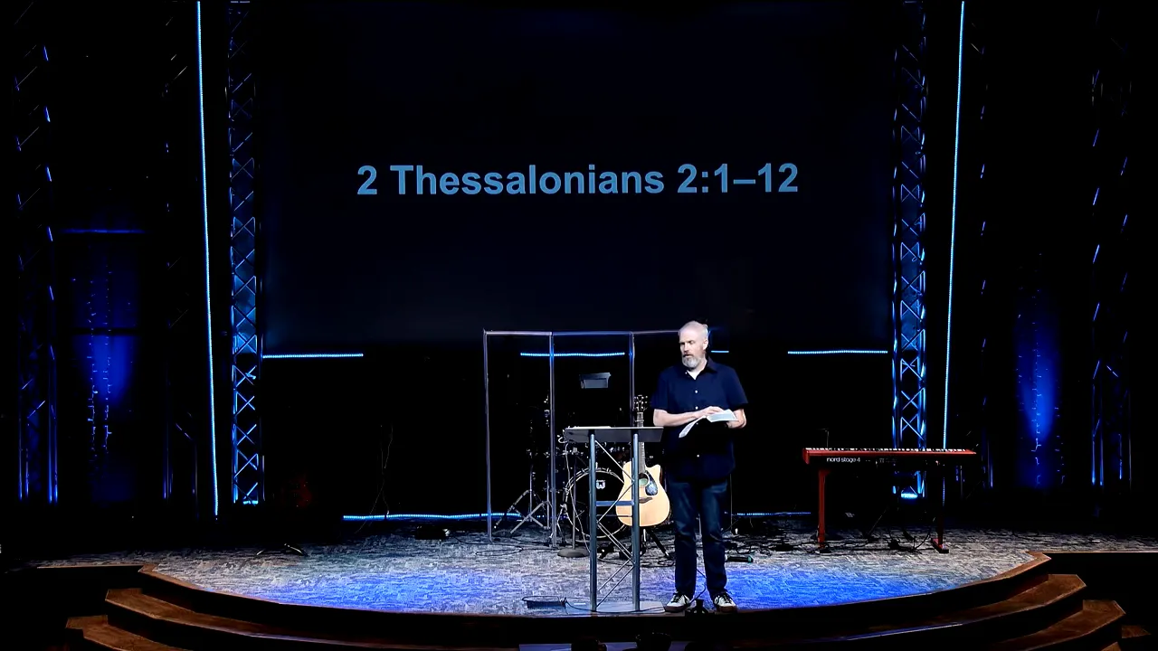 Pastor teaching at a church stage with a large screen reading “2 Thessalonians 2:1–12”