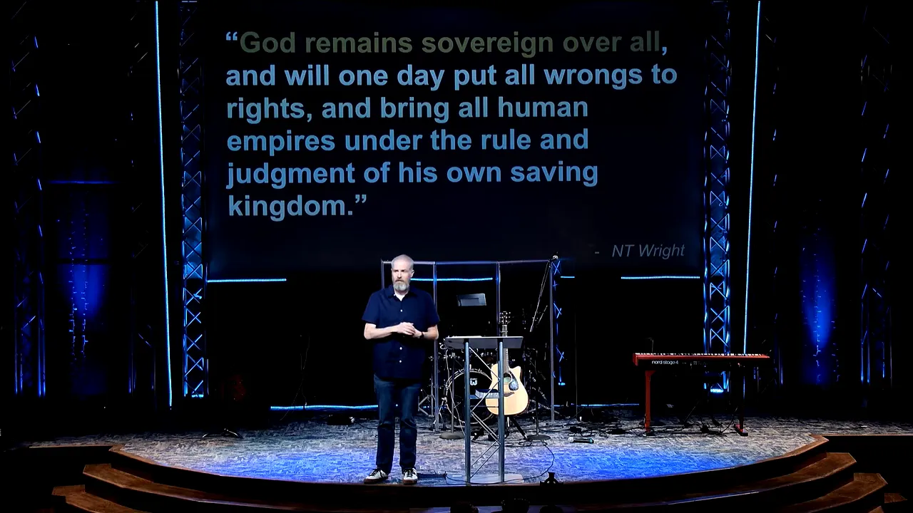 Pastor standing on stage with large screen quote about God’s sovereignty over all