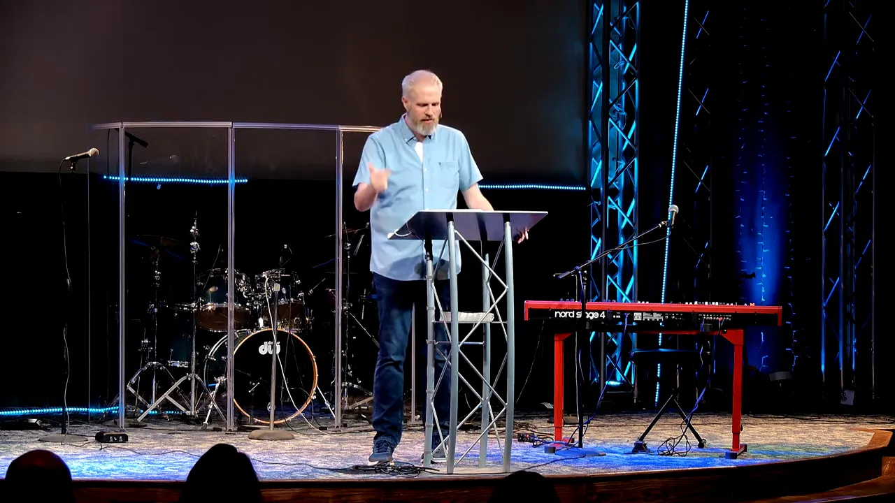 Pastor speaking at a lectern on stage about remembering identity in Christ and overcoming fear