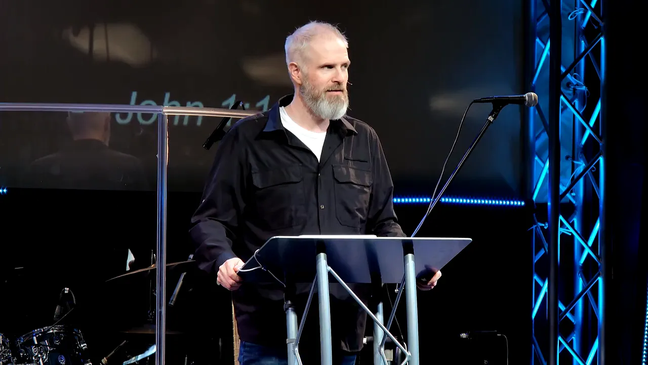 speaker at lectern explaining the incarnation with blue stage lighting