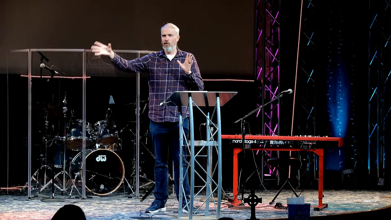 Speaker gesturing broadly beside a lectern during a sermon referencing Resurrection Sunday