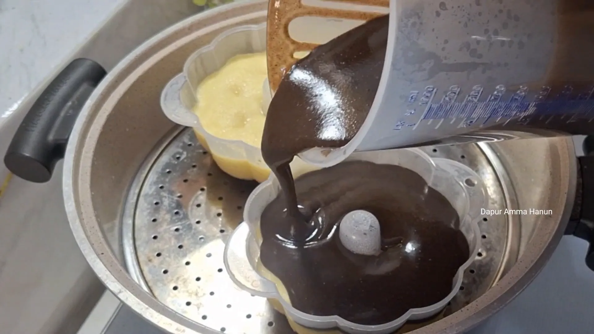 Menuang adonan brownies ketan hitam di atas adonan keju kukus