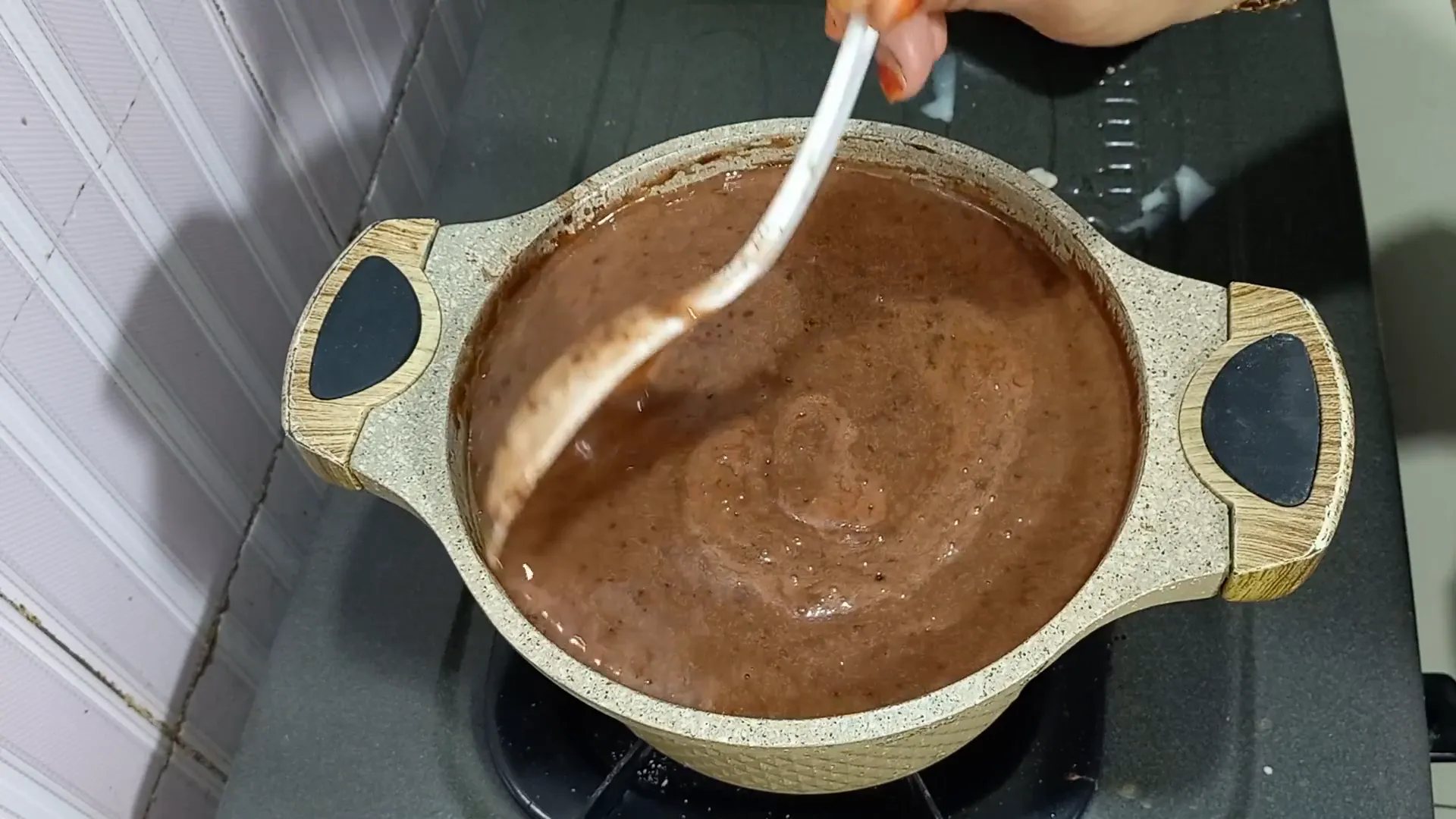 Puding coklat mulai mengental dan meletup-letup saat dimasak