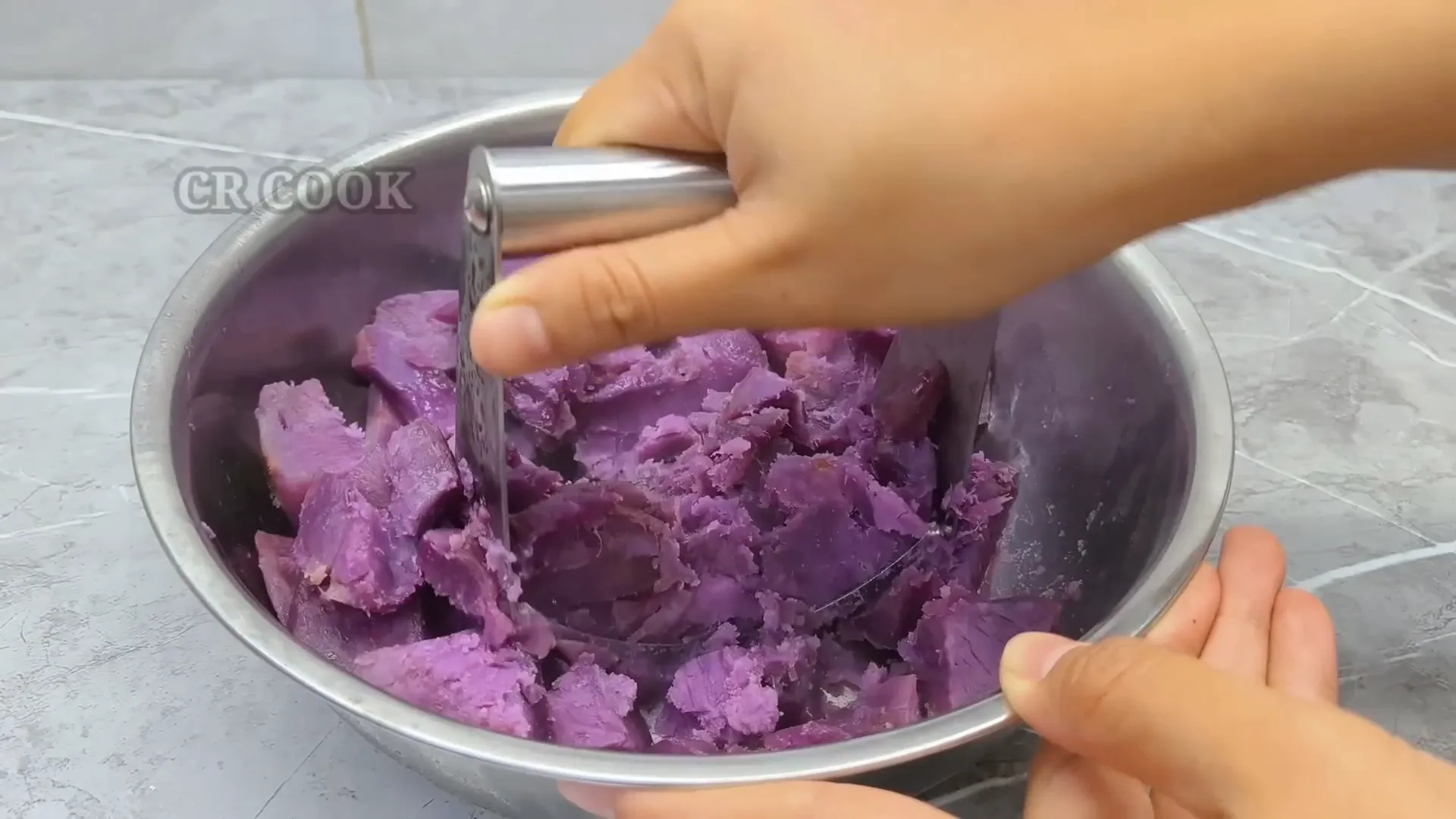 Menghaluskan ubi ungu menggunakan alat penghalus kentang
