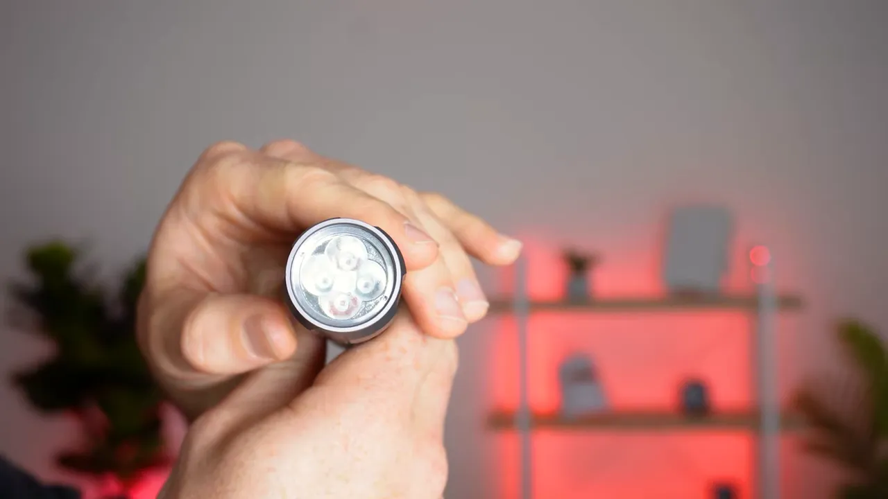 Close-up of red light therapy torch head showing LED array held by hand