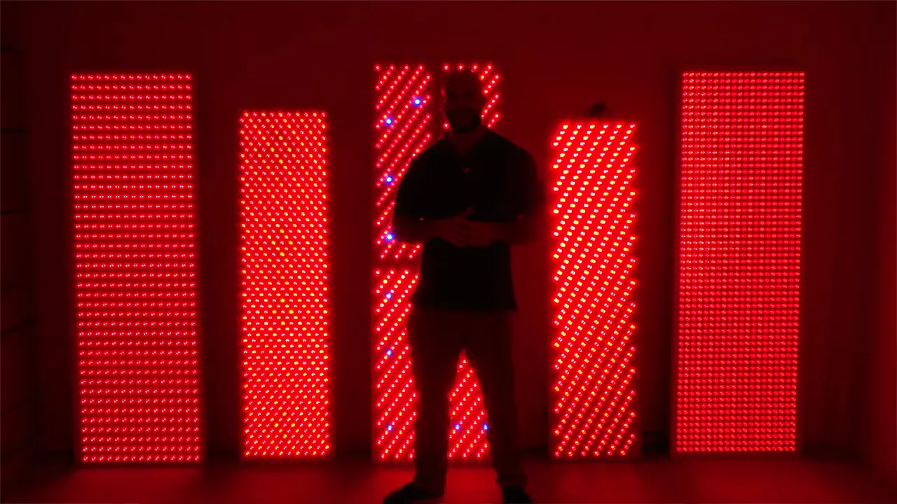 row of large red light therapy panels with person silhouette in front