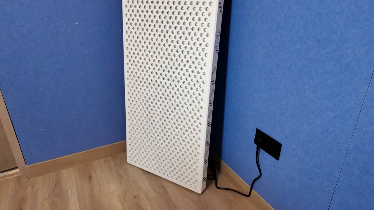 full view of the Block Blue Light Ultimate XXL panel leaning against a blue wall with power cord plugged in