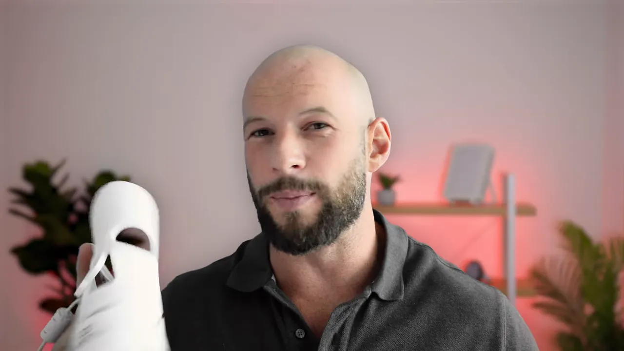 Presenter holding the LumaLux Pro LED face mask upright in a studio setting