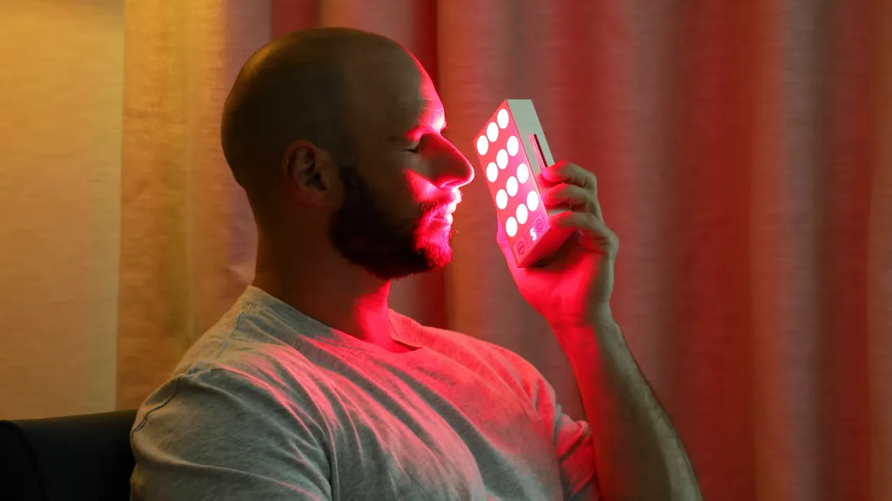 Person using the Mito Mobile Flex handheld device on their face with red LEDs visible
