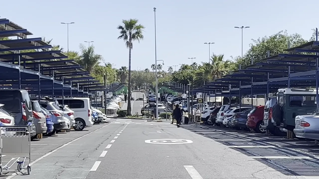 Tenerife South Airport guide - arrivals, departures, taxis, buses and car hire 5 Shaded airport rental car park with rows of vehicles and a traveller with luggage approaching the bays