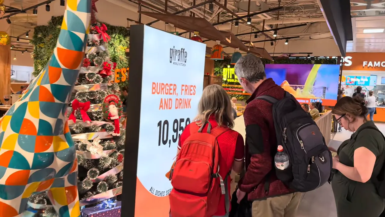 I Almost Missed My Flight - Tenerife South Airport Delays and How to Avoid the Stress 5 Passengers checking a digital menu at the Giraffe restaurant with the giraffe statue and festive decor at Tenerife South Airport