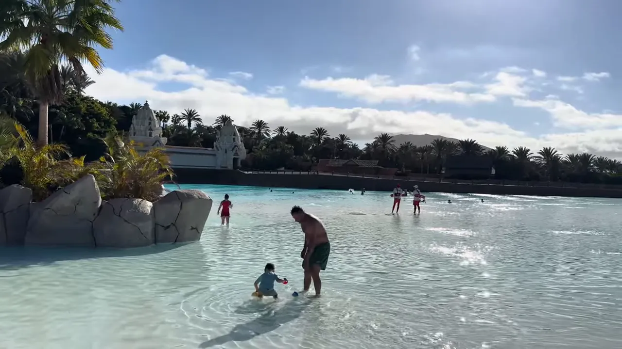 Wide view of Siam Park wave pool with swimmers and palm landscaping