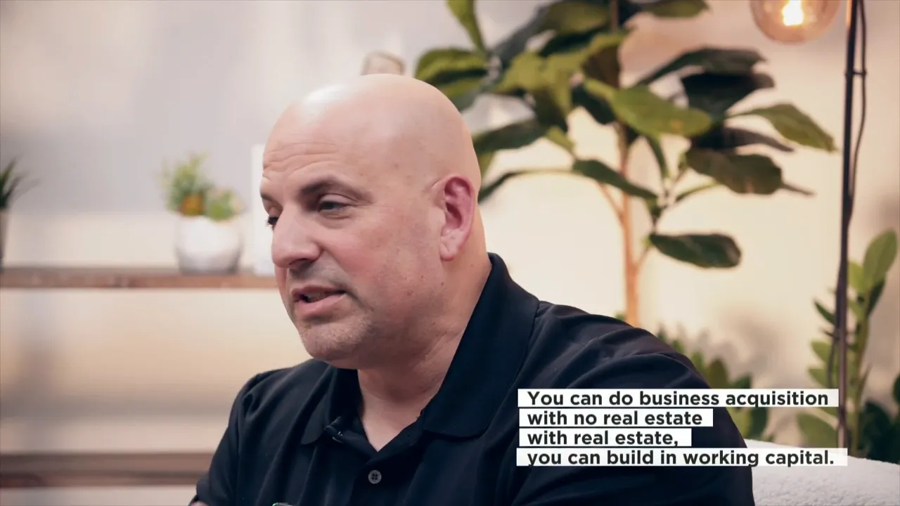 Interview screenshot showing on-screen text stating that business acquisitions can be done with or without real estate.
