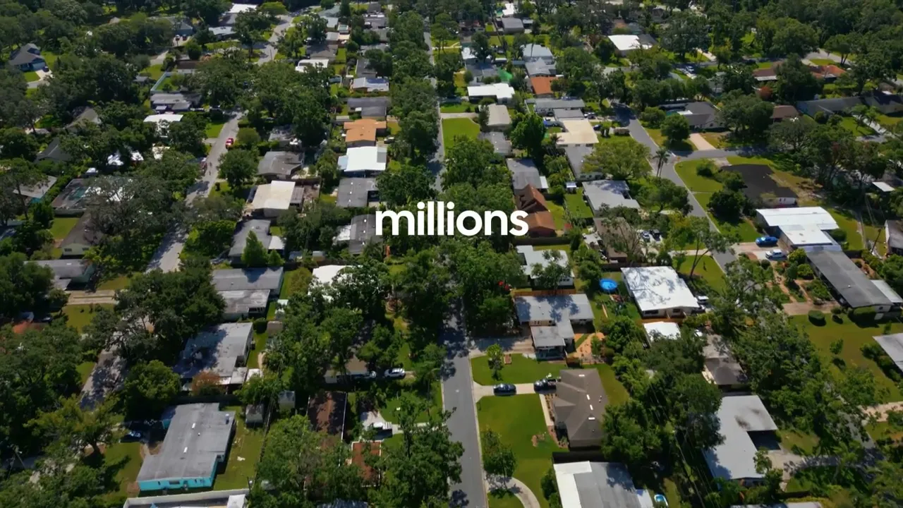 Aerial color view of a suburban neighborhood showing many single-family homes from above with the word 'millions' overlaid.