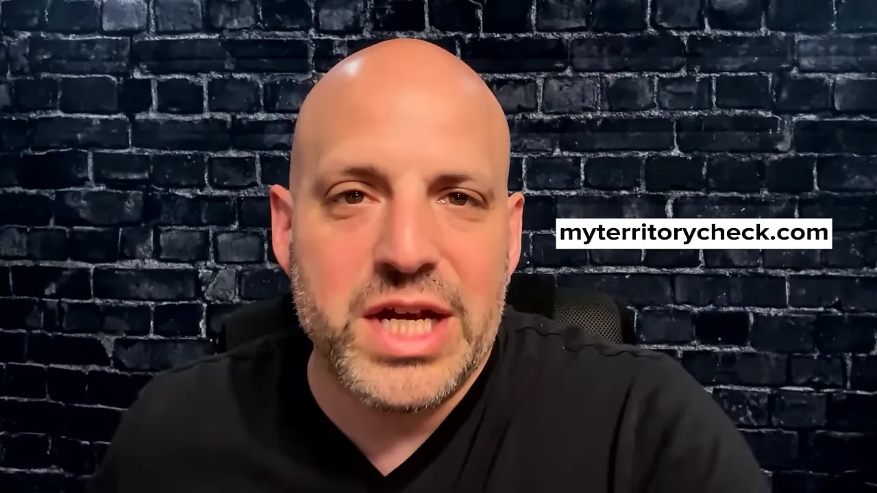 Presenter speaking against a brick background with on‑screen overlay 'myterritorycheck.com' to illustrate territory checks.