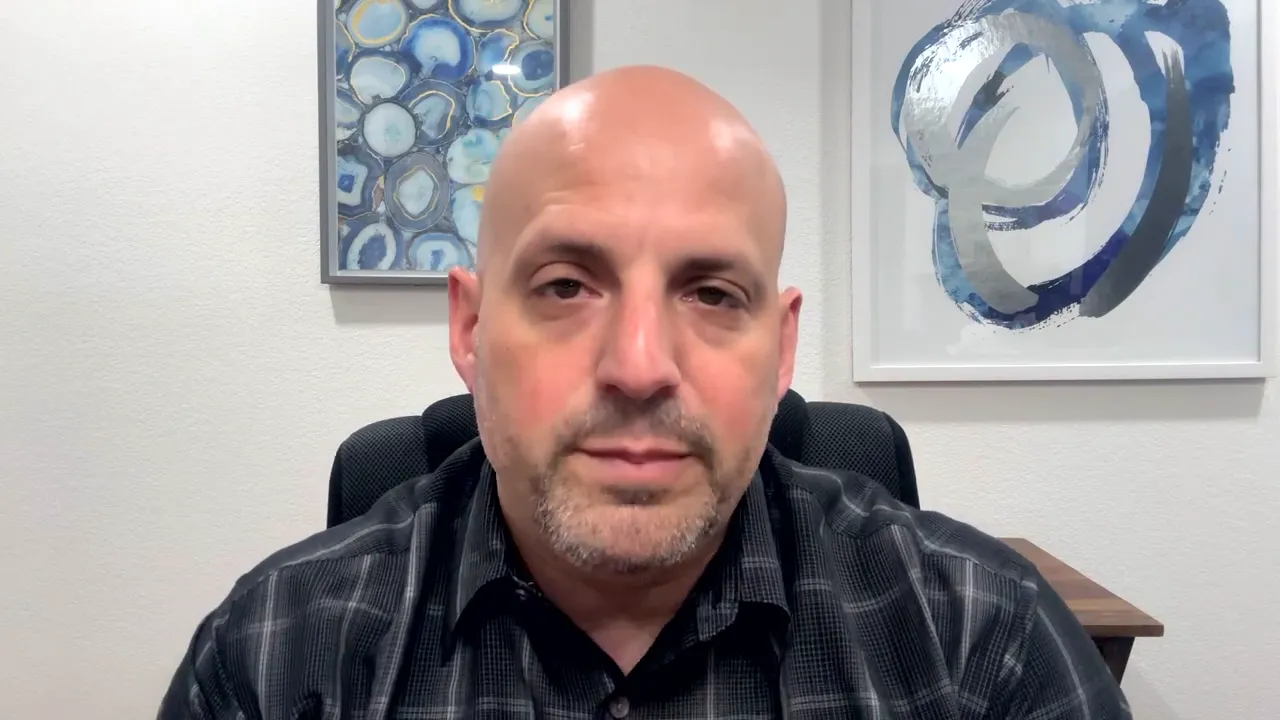 Business coach explaining SBA expansion financing in office with abstract artwork behind him