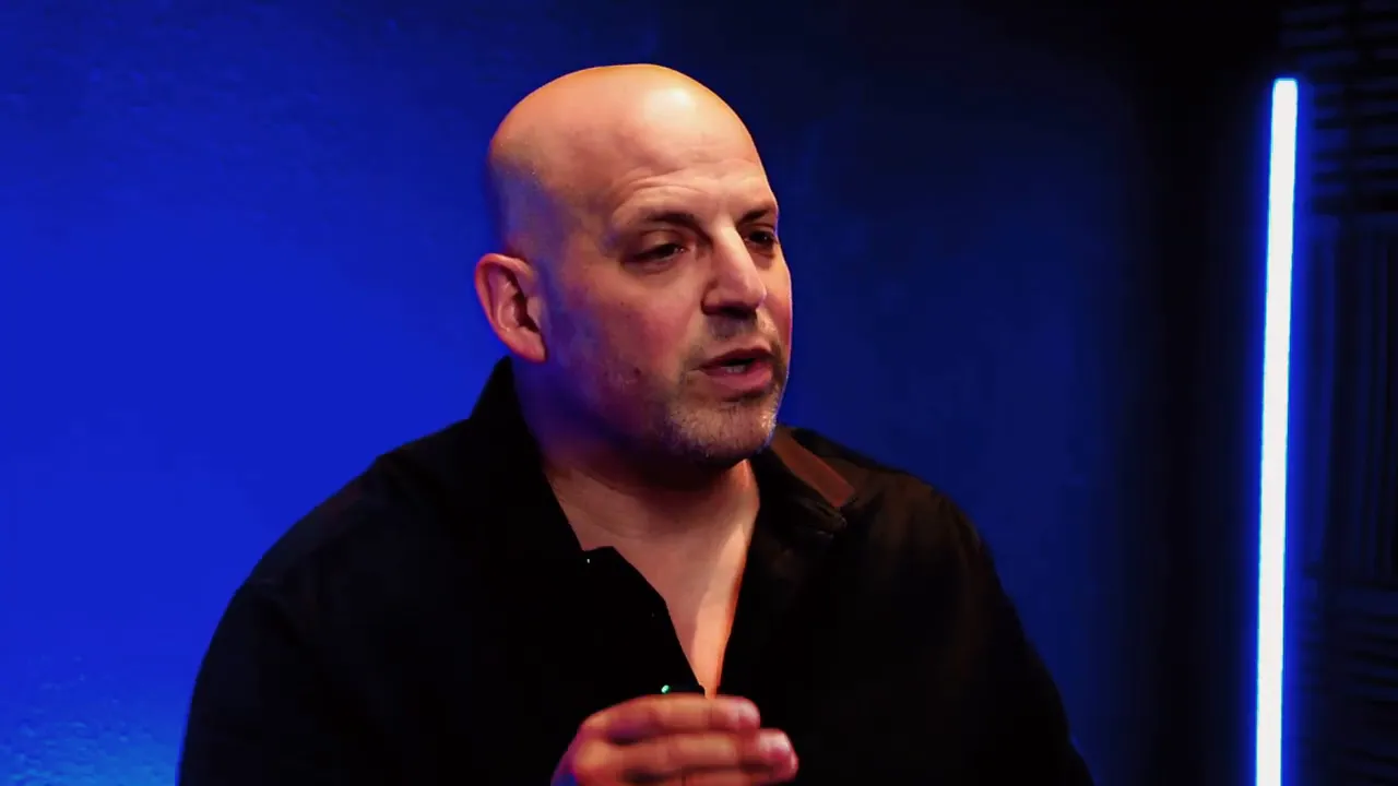 Podcast host speaking about risks of buying a business, blue studio background