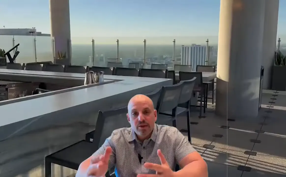 Presenter at a rooftop bar seating area with city view behind