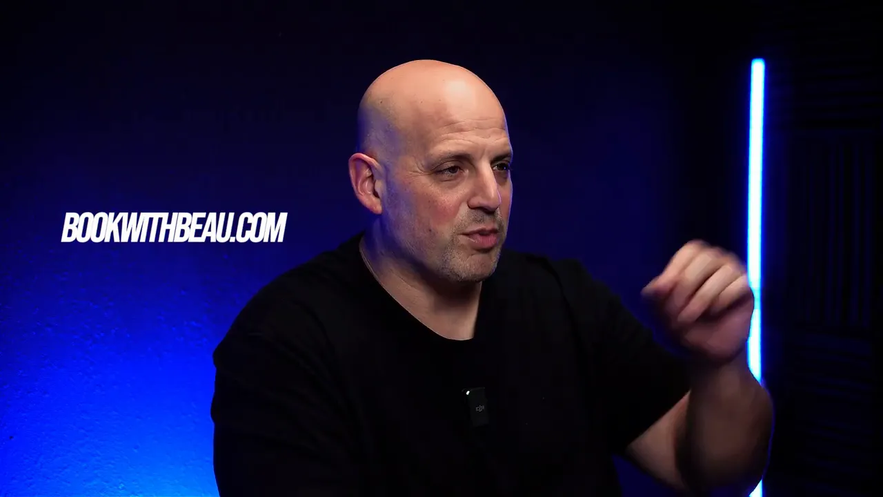 Speaker gesturing in blue-lit studio with 'bookwithbeau.com' graphic on the left.
