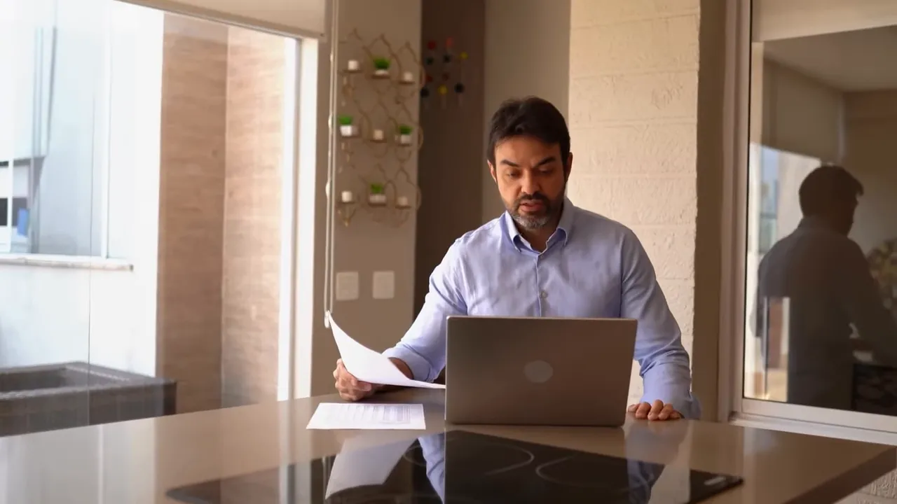 Person reviewing business documents and working on a laptop at a countertop