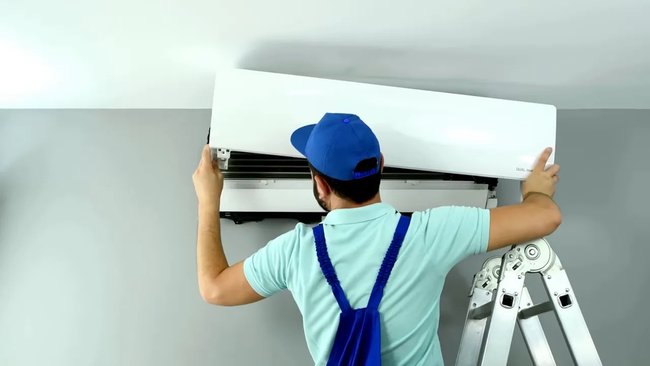 Technician on a ladder installing a wall-mounted air conditioning/HVAC unit