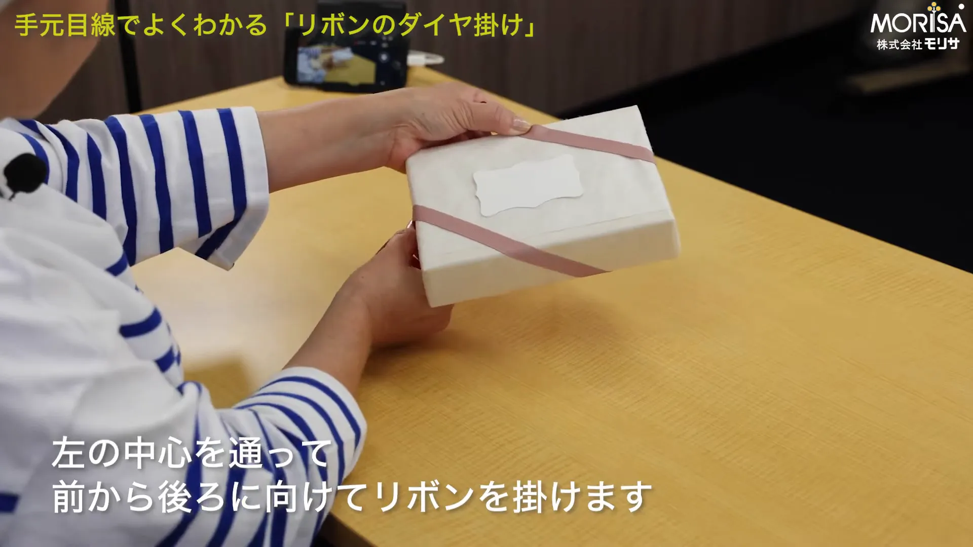 箱の表面に戻ってきた両方のリボンが見え、ダイヤ模様の土台を作る手元の写真