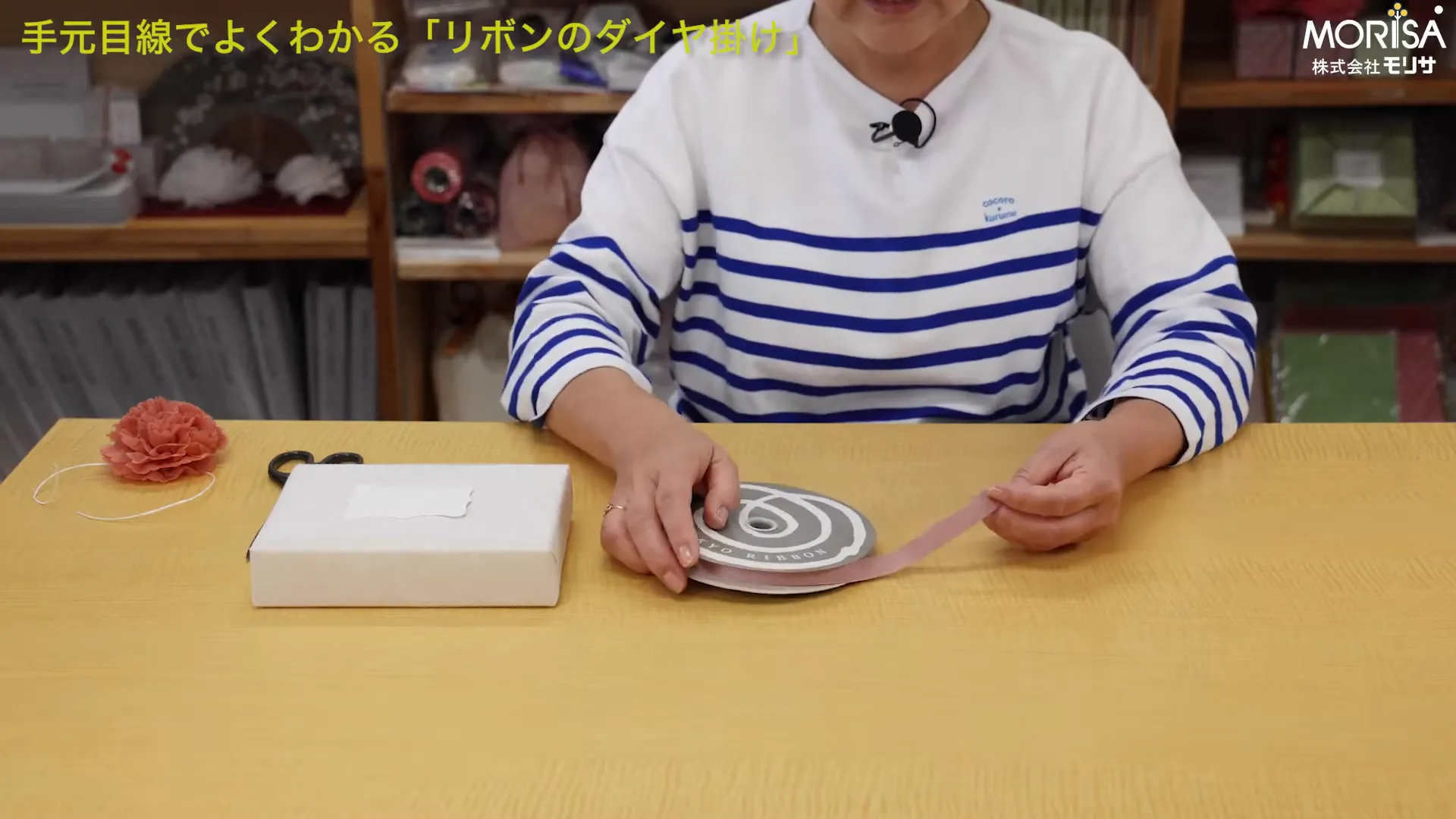 テーブルに並べたラッピング用品（箱、グログランリボンのボビン、はさみ、造花）