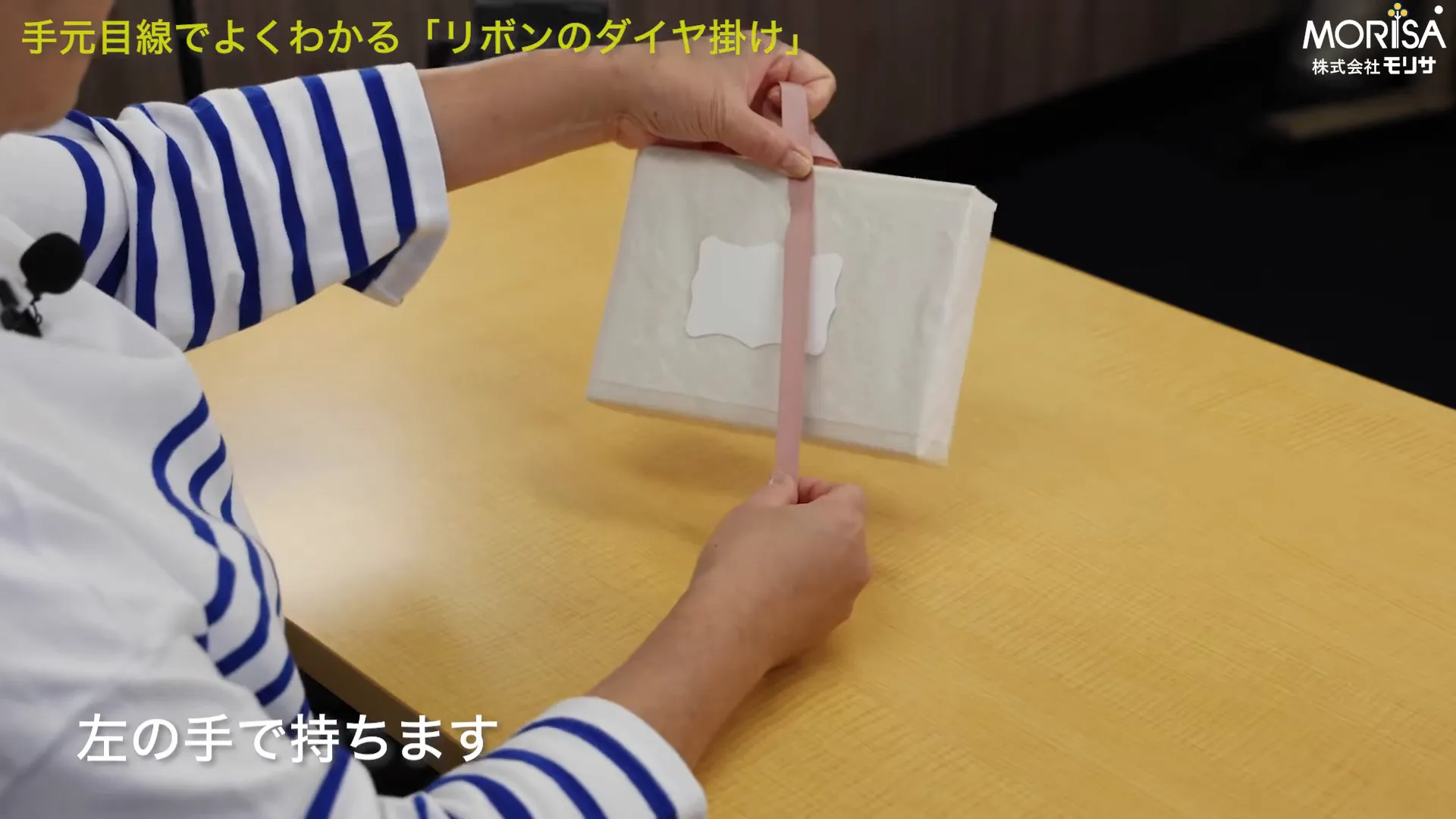 箱の中心にリボンを当てて位置を確認する手元の全体像
