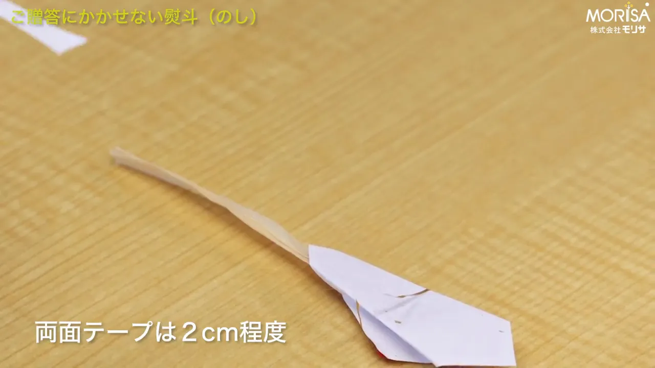 のしの裏面に2cmの両面テープを貼る作業のクローズアップ