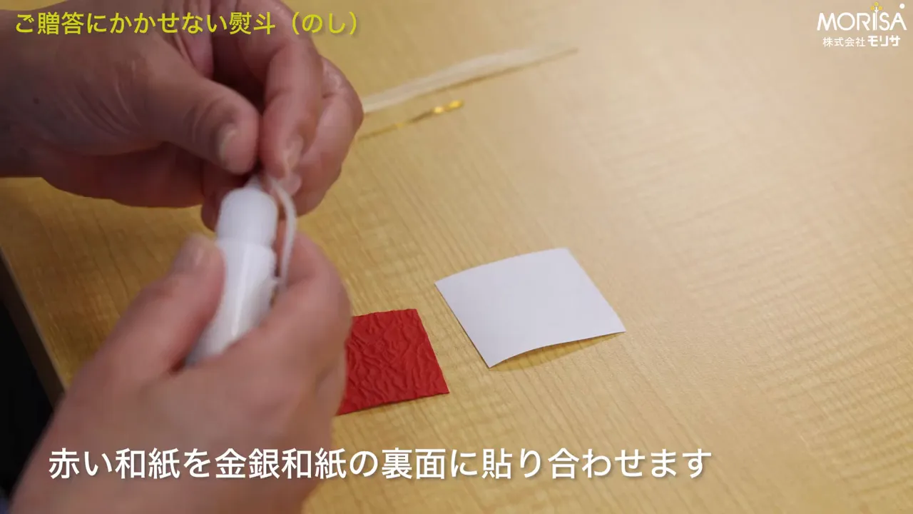 白と赤の和紙を並べ、接着具で貼り合わせる手元の写真