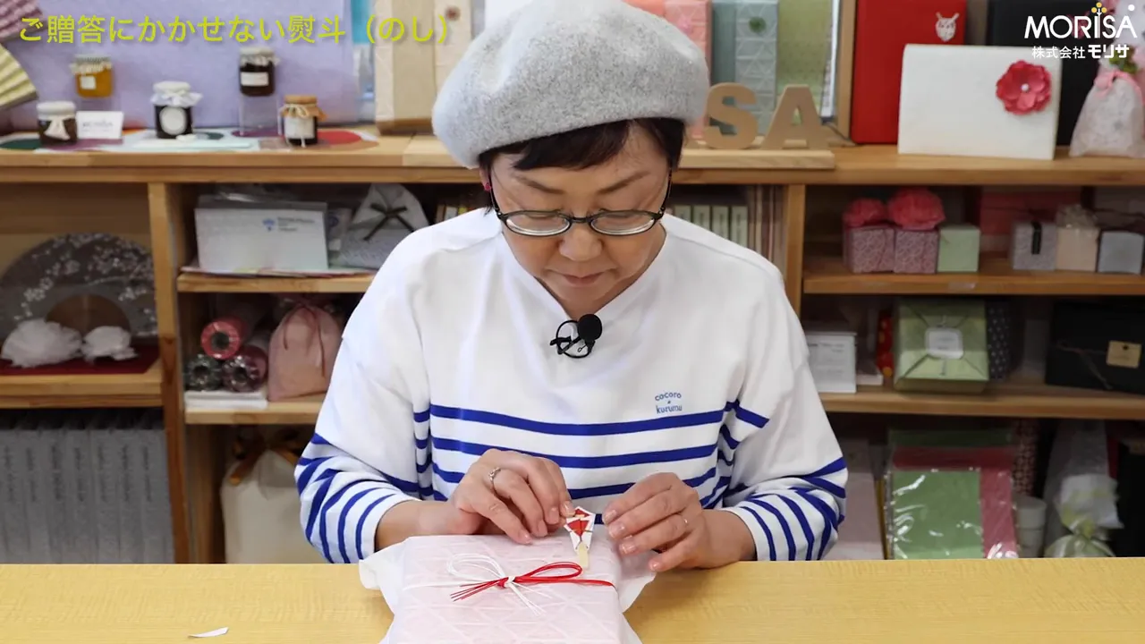 包みの上にのしを丁寧に置く講師のショット（のしが箱の上にある）