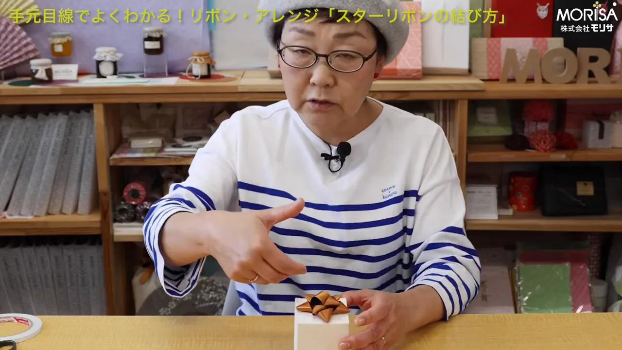 講師が完成したスターリボンを指さしながら失敗しやすいポイントを説明している手元とリボン