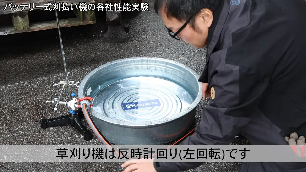 たらい水流実験で草刈り機が反時計回り（左回転）である説明付きの様子