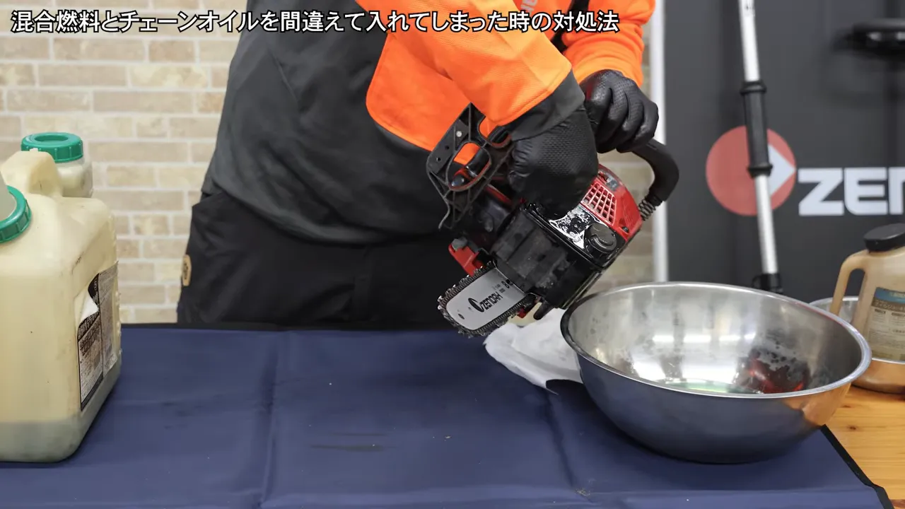 チェンソーを金属ボウルの上で傾けて洗浄液を抜く様子