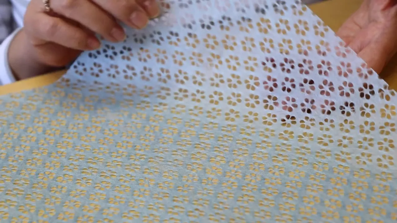 小さな花柄の透かし模様が入った薄手の紙をめくる手元のクローズアップ写真