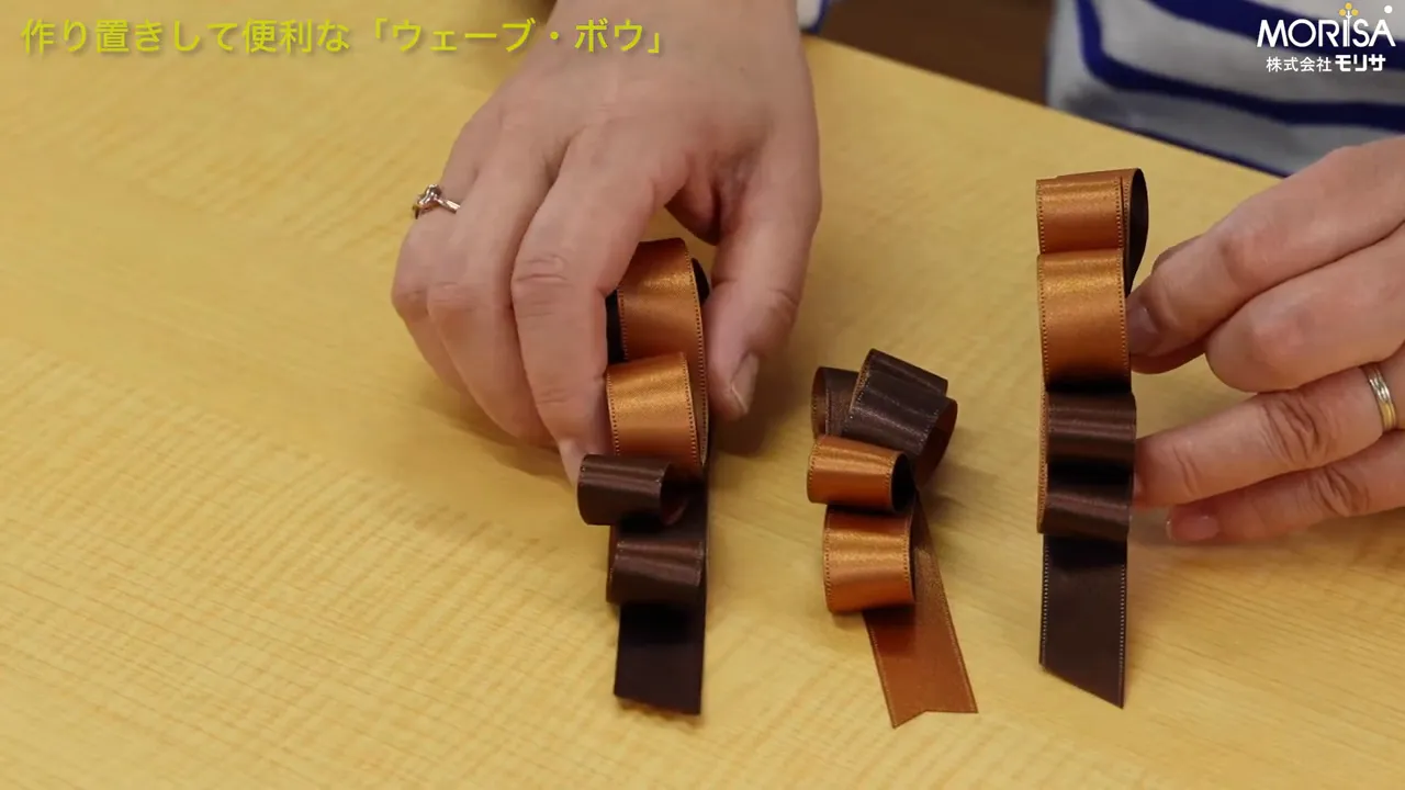 三つのウェーブボウをテーブルに並べ、手で形を整えている様子（尾の切り方がはっきり見える）