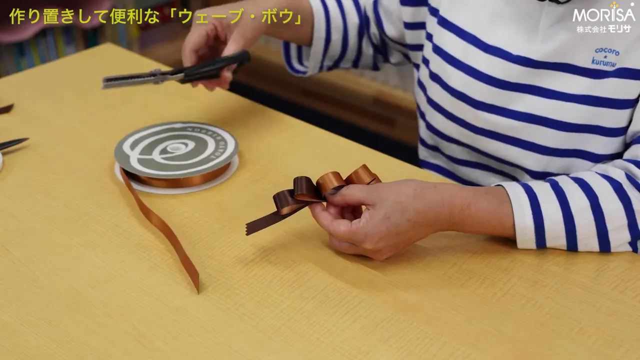 ピンキングはさみでリボンの端をギザギザに切る手元のクローズアップ