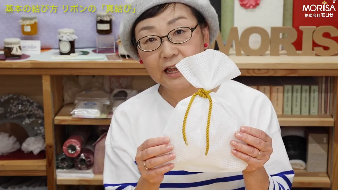 正面から見た白い袋の真結び、黄色いコードと手元がはっきり見える