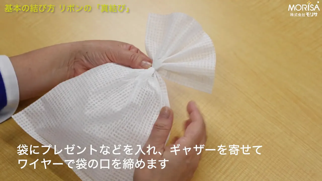 袋の口をギャザーで寄せ、中央をつまむ手元のクローズアップ