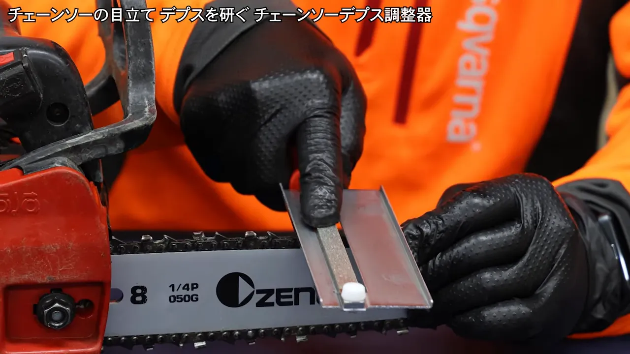 gloved hand filing a chainsaw depth gauge with the integrated diamond file tool