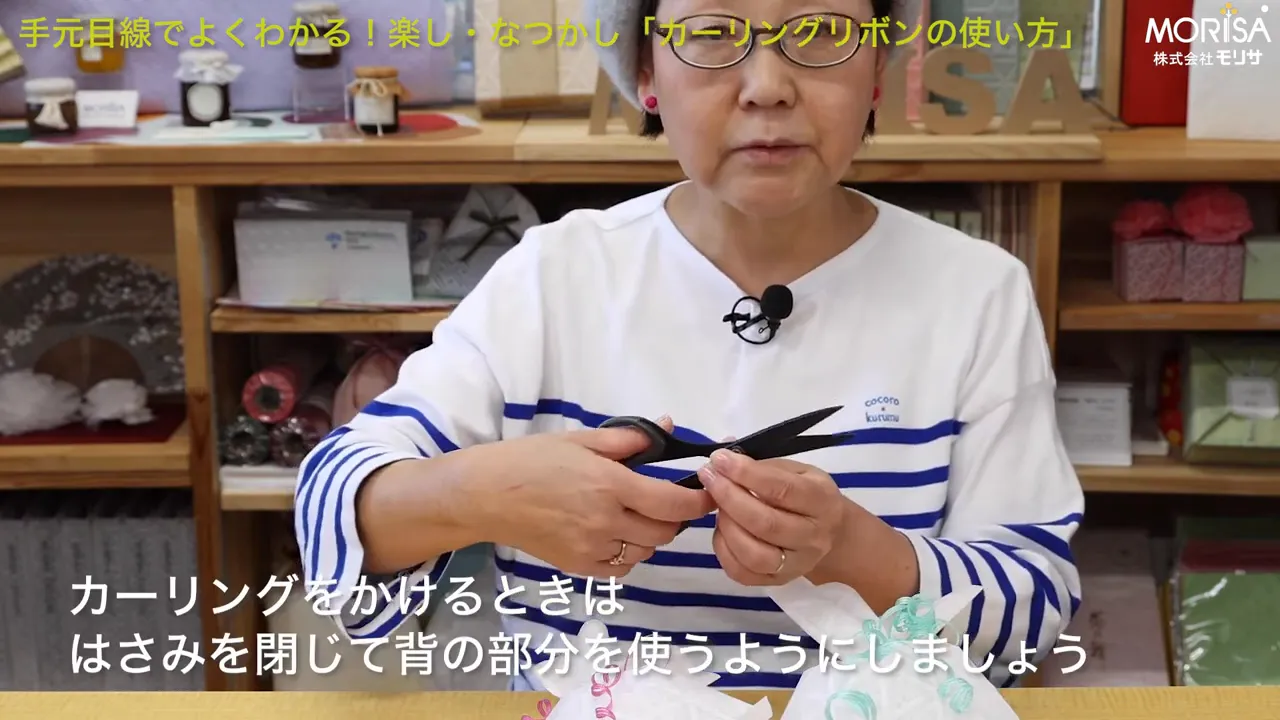 はさみの背でリボンをしごく手元を示す実演ショット