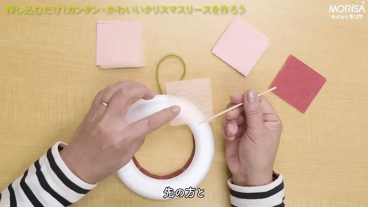 竹串を持って和紙を発泡スチロールリースに差し込もうとしている手元の写真