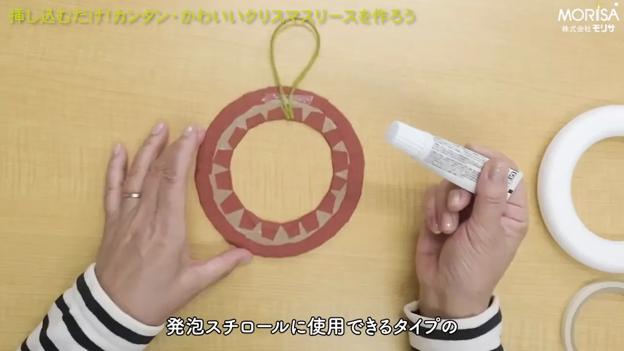 発泡スチロール用接着剤のチューブを持つ手元とリース台、発泡スチロールリースが並んだ作業風景