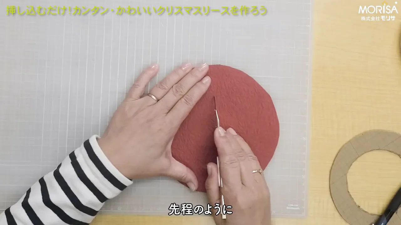 カッターナイフで和紙の円形パーツに切り込みを入れている手元のクローズアップ