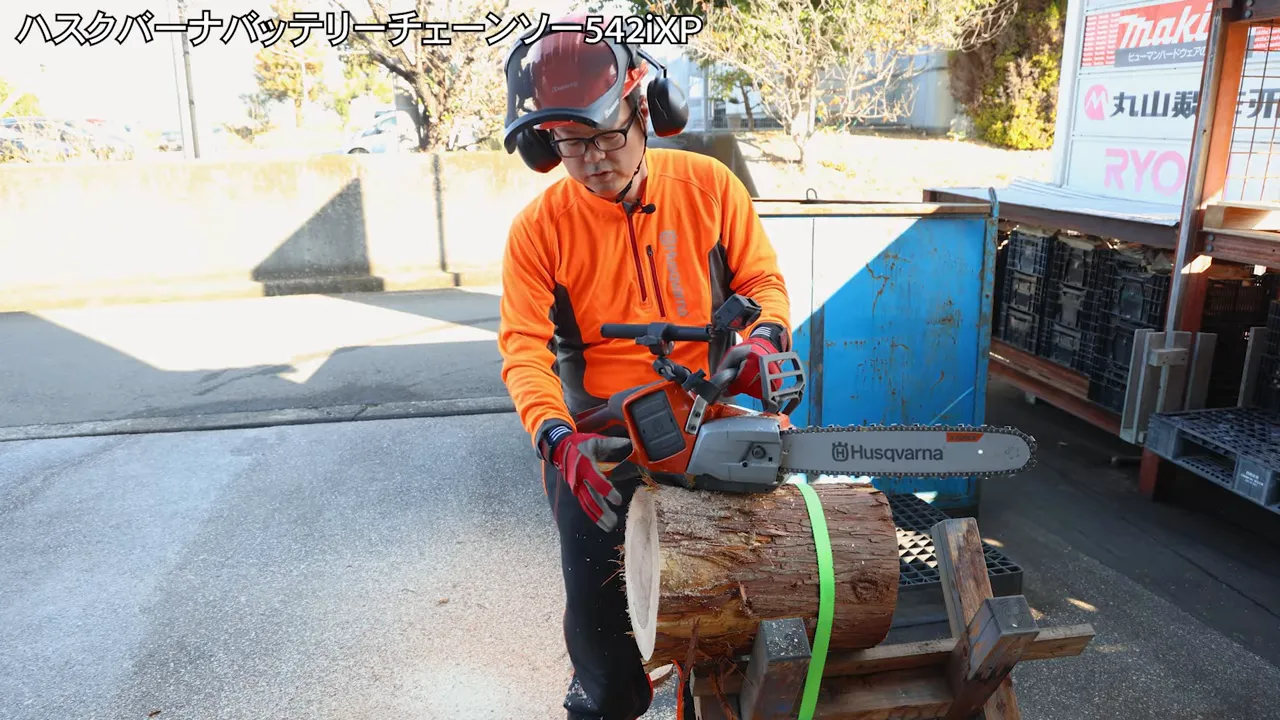 ハスクバーナ 542iXPで太い丸太を切る様子（作業者とチェーンソー、切りくずが見える）