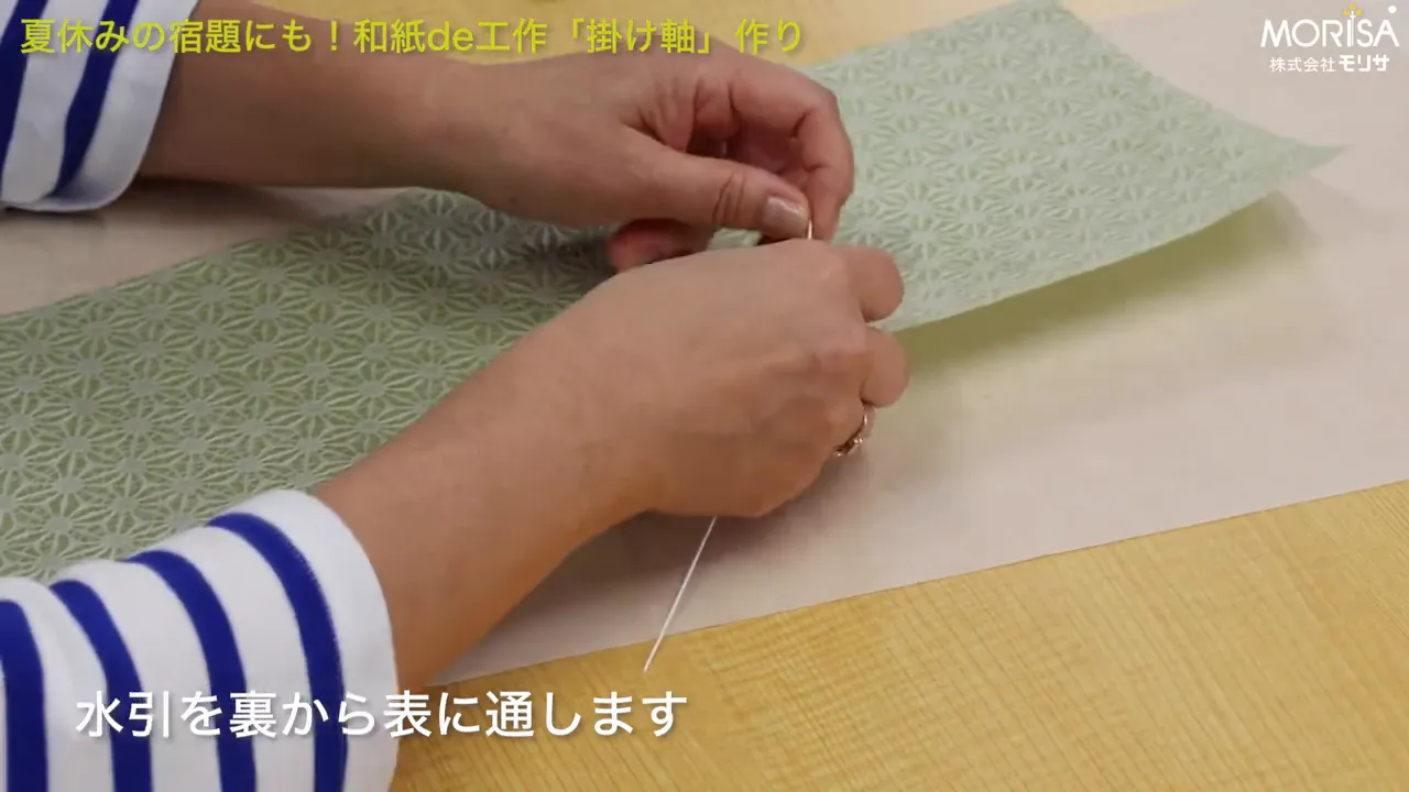 水引を穴に通して結んでいるシーン