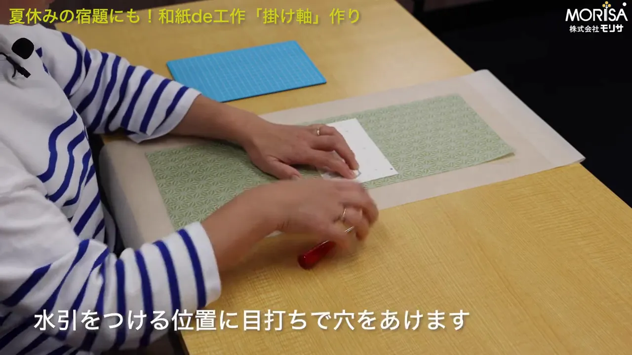 マットの上で目打ちを使い穴をあけている様子